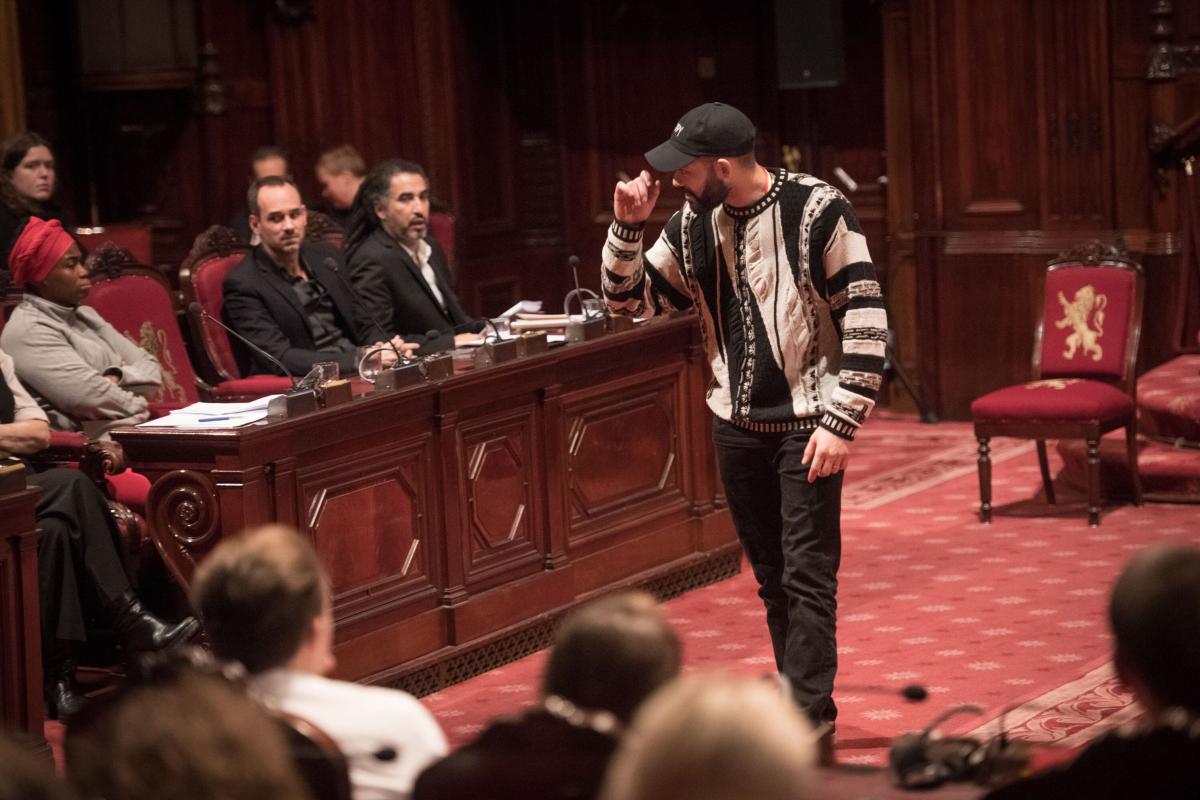 Beeld uit De Waarheidscommissie in Brussel (2018) Acteur maakt zich kwaad, links zitten drie getuigen te luisteren naar zijn getuigenis.