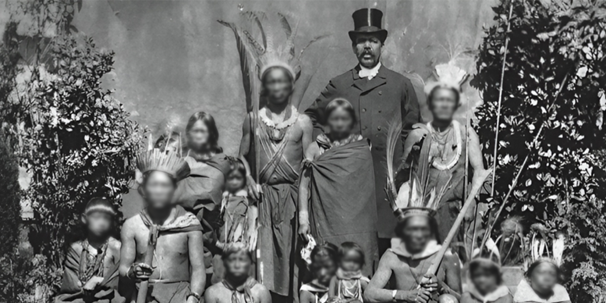 Groepsportret van Surinaams inheemse mannen, vrouwen en kinderen met ronselaar William Mackintosh op de wereldtentoonstelling 1883 in Amsterdam. 